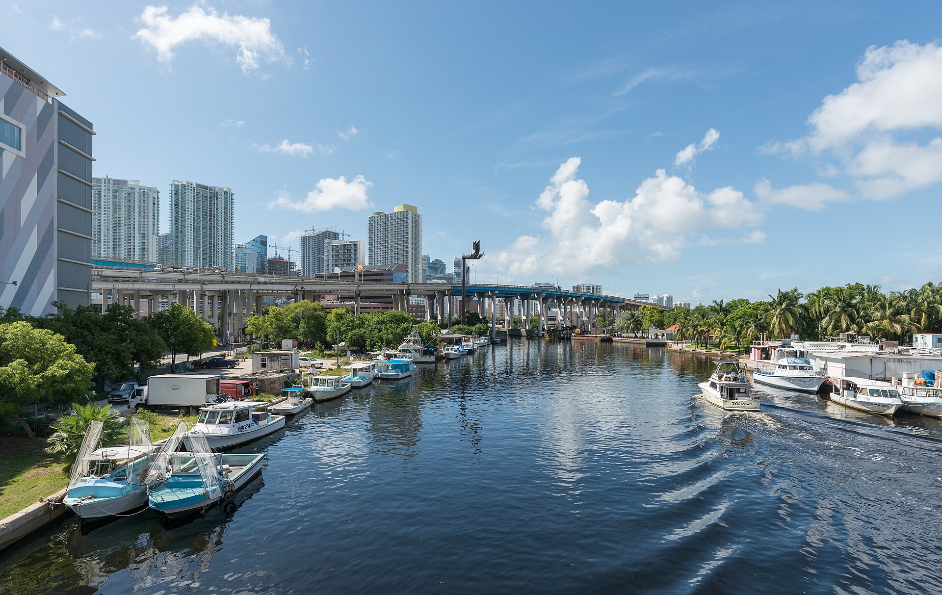 Miami River with moored boats and downtown towers under blue sky