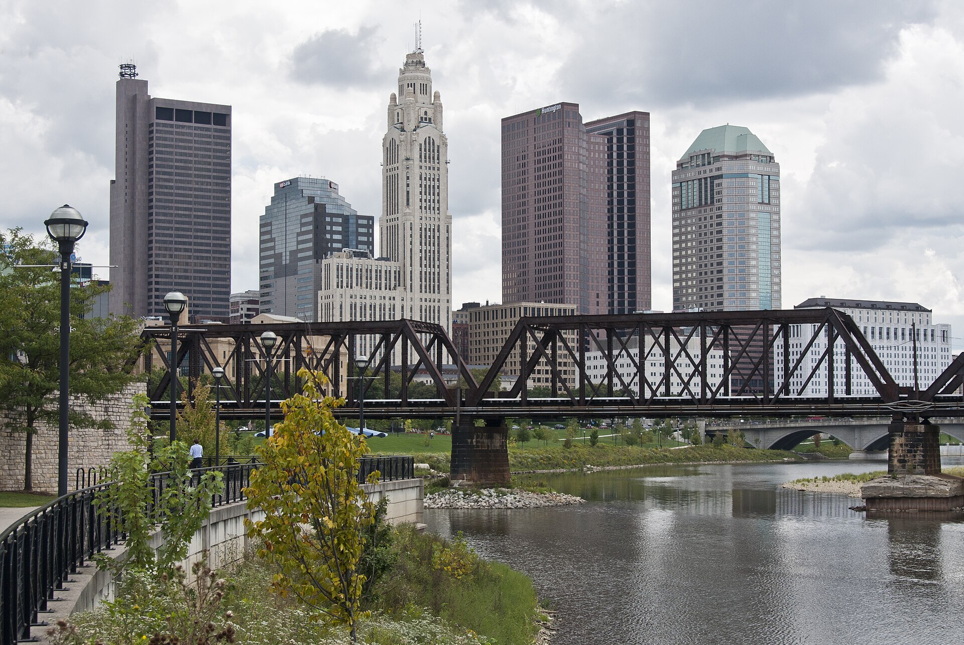 Downtown Columbus skyline behind a steel railroad bridge over the Scioto River