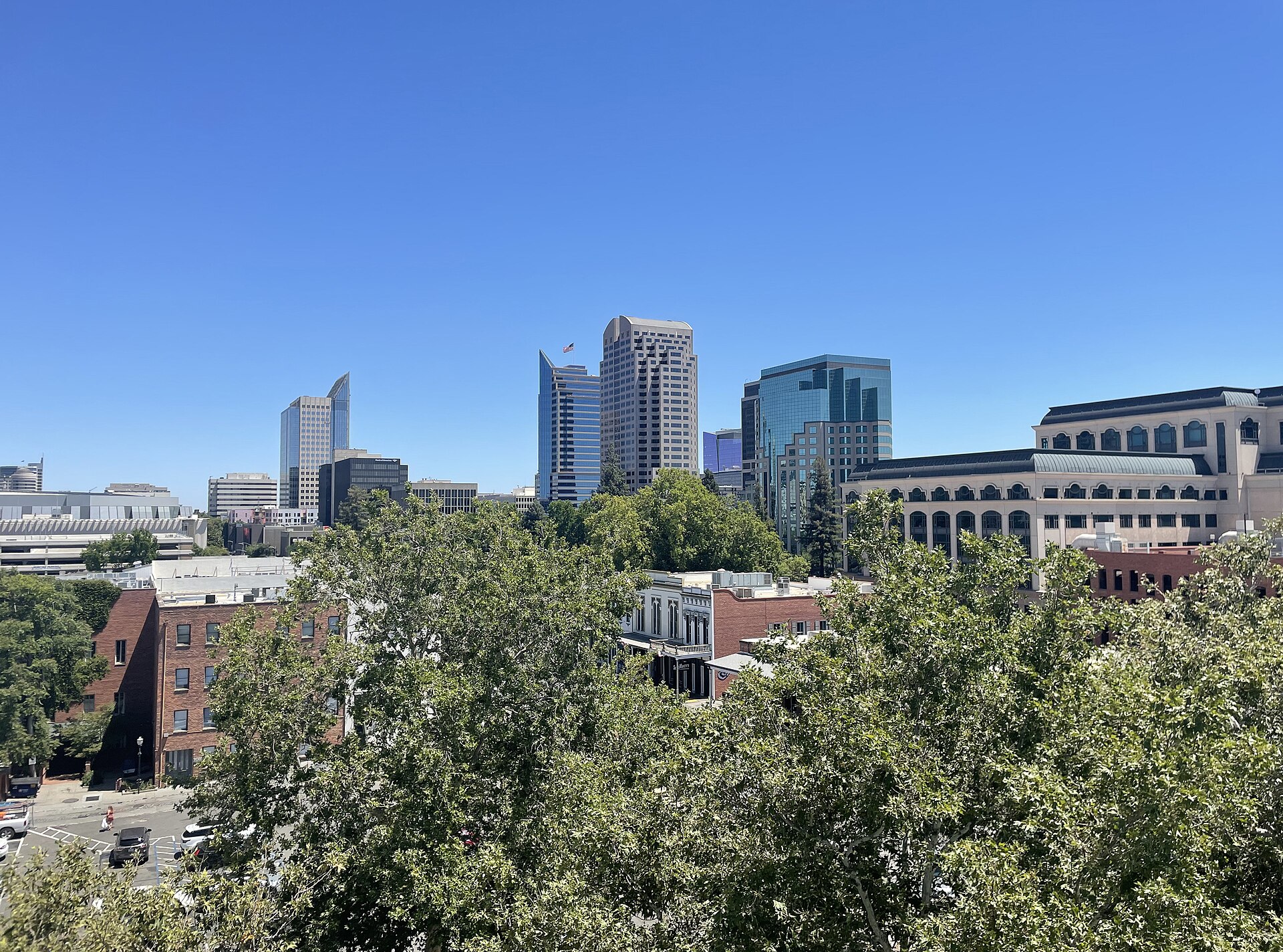 Downtown Sacramento towers above tree canopy and Old Sacramento rooftops